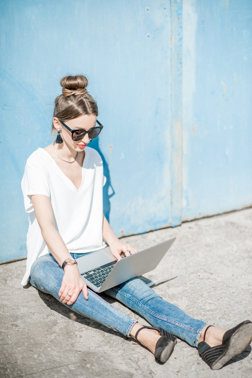 Woman Working with Laptop on the Blue Wall Background